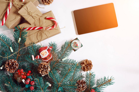圣诞节在线购物背景。平板电脑屏幕复制空间，云杉枝，白色背景上的礼物。太阳耀斑