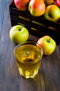 在玻璃和熟透了的苹果木制的桌子上的苹果汁