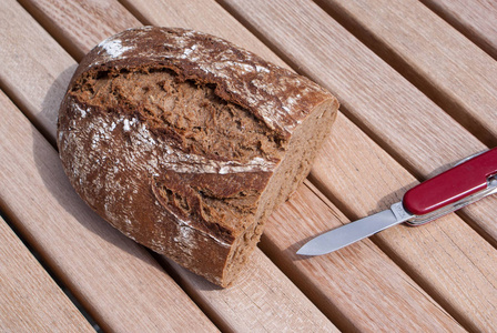 用刀在旧木桌上铺设的黑麦面包