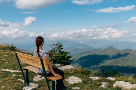 时髦少女享受着的山谷坐在板凳上岩顶上的景色。对背景谷景观旅游旅行