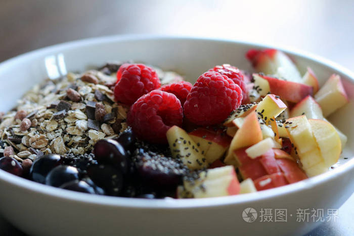 混合的水果和谷物在褐色的木桌上的白碗