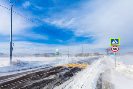 冬季降雪暴雪雪灾和能见度低的道路上有人行横道公交车站和路标。驾驶汽车时的危险雪路