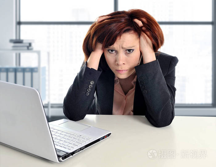 现代办公室窗口内拉扯她的头发在压力中工作的伤心和失望的年轻商业