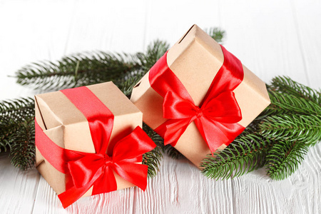 工艺礼品盒用红丝带和蝴蝶结，绿色的圣诞树，装饰，白色木制背景上。圣诞节和新年贺卡 横幅 传单