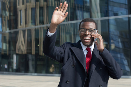 打招呼表情他看到大街上的非洲帅哥在眼镜, 领带和黑色外套谈手机与