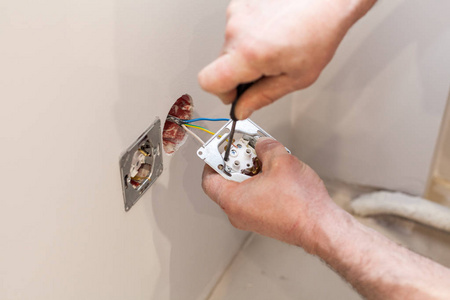 手中的电工安装墙上电源插座照片