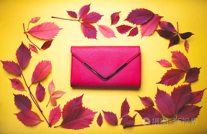 在秋天的黄色背景上的红色手提包