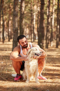 英俊的年轻男子与一只拉布拉多犬在户外在森林里