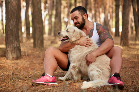 英俊的年轻男子与一只拉布拉多犬在户外在森林里