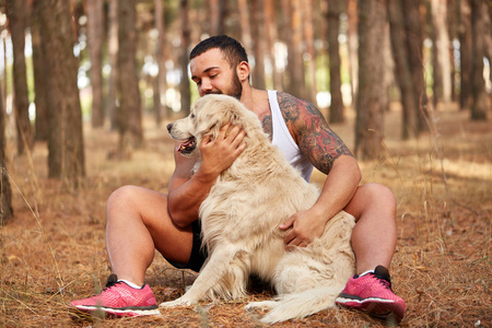 英俊的年轻男子与一只拉布拉多犬在户外在森林里