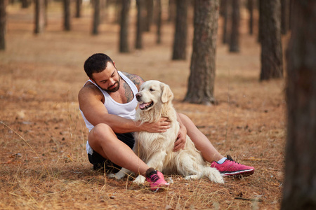 强壮的黑发男人与拉布拉多狗走在森林户外照片