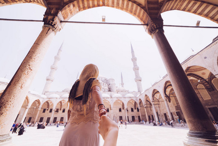 女人想要她的男人跟着她在假期前在土耳其，伊斯坦布尔的蓝色清真寺。跟着我的概念