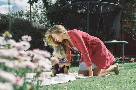 一个年轻的金发女人，带着一个可爱的男孩在户外绿草地上