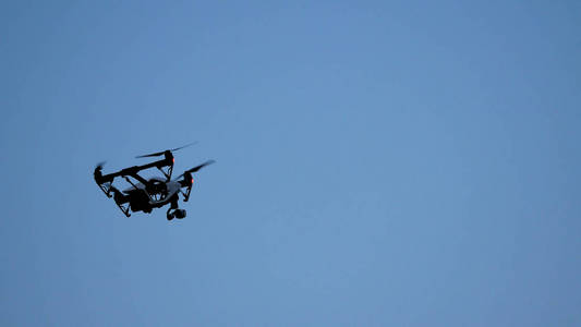 黑色的无人机 quadcopter 相机飞越蓝蓝的天空.