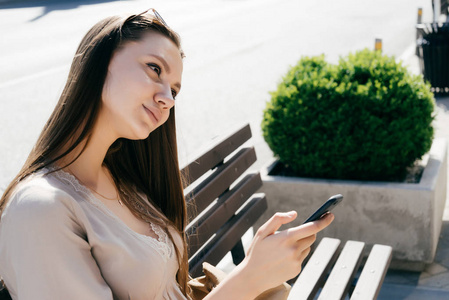 手机在手微笑若有所思地看着别处的女孩照片
