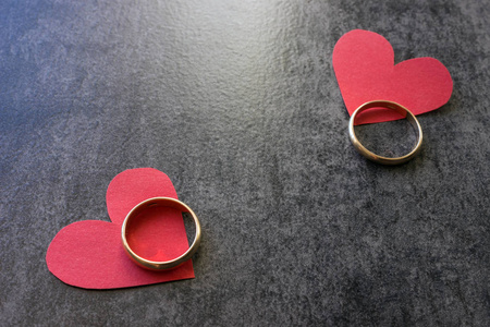 结婚戒指和红色的心。黑色背景