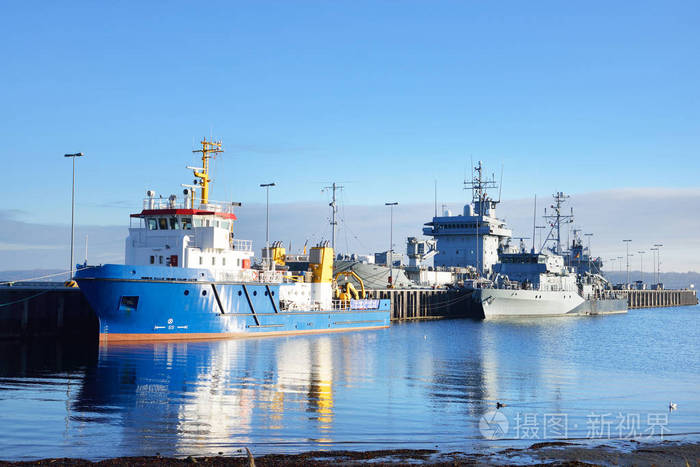 系泊的拖船和军舰在码头上