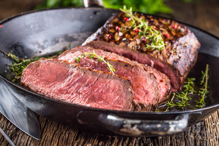 牛肉牛排。在平底锅上木板用刀和叉草本香料和盐肋眼牛排片多汁中等