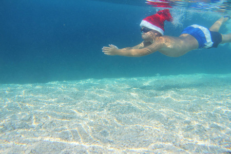 圣诞老人的帽子在海中游泳的男孩