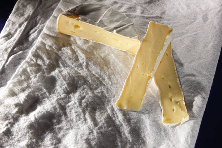 卡门培尔奶酪奶酪切上白色亚麻餐巾在复古的风格设计器