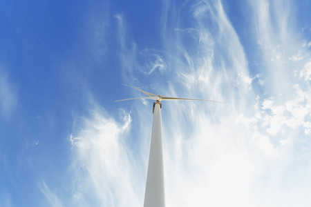 从巨大的高白色电动风车底部看到明亮的蓝天背景。 生态旋转风力涡轮机。 可持续电力和现代技术。 复制空间。