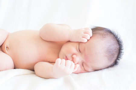 可爱的婴儿婴儿两周睡在床上，白色背景概念国际日的女童苹果眼基督教洗礼新生儿婴儿