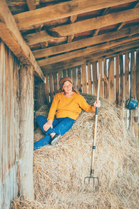 一个成熟的女人在一个农场工作时休息躺着，一根稻草