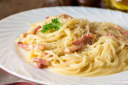 经典的面食 carbonara。意大利面配培根，鸡蛋蛋黄和帕尔玛奶酪在白板上深色木制背景