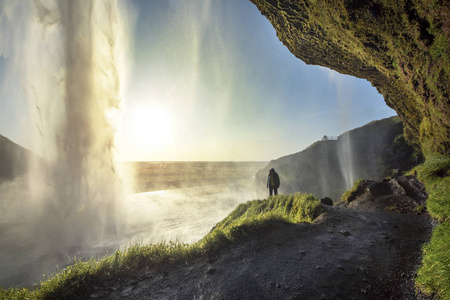 游客站在 Seljalandsfoss 在冰岛南部，Seljalandsfoss，冰岛最著名的瀑布之一