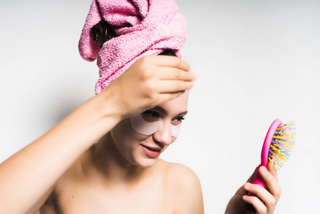 女孩用粉红色毛巾上她的头和她的眼睛看着一面小镜子下的修补程序