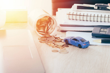 汽车保险和 loanconceptCar 玩具与资金流出罐子硬币银行，温暖的色调过滤器的桌子上