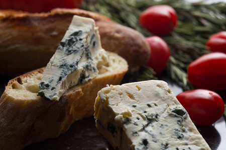 蓝纹奶酪与法国法棍面包 番茄和黑色大理石桌上的草药。在法国和意大利的传统小吃