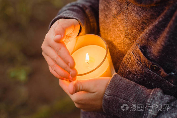 一支燃着的蜡烛在一个孩子的手中