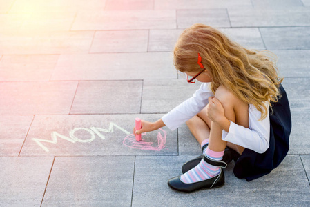 一个小小的可爱女生绘制彩色粉笔在人行道上的爱你的妈妈