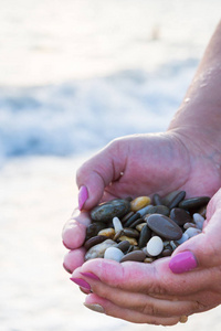 海石在日落海滩上的手中