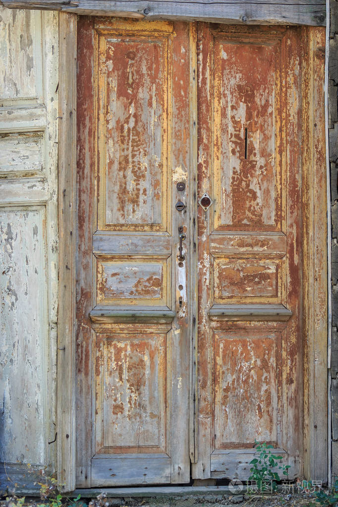 破旧的大门棕色漆带有把手和锁作为被遗弃的生命的象征的遗骸照片-正