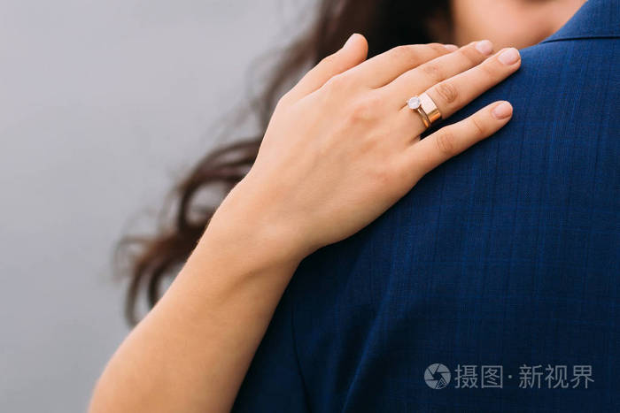 女人的手特写拥抱她的男人穿着蓝色西装的肩膀
