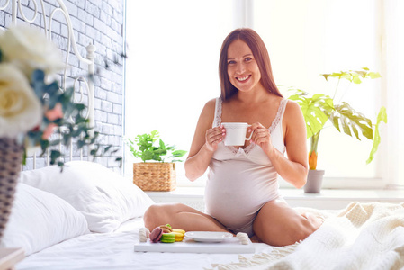 孕妇喝一杯茶与杏仁饼在床上