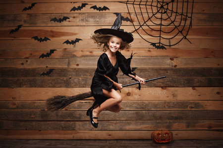 万圣节女巫概念   蝙蝠和蜘蛛 web 背景上魔法扫帚飞越的白种人的巫婆小孩