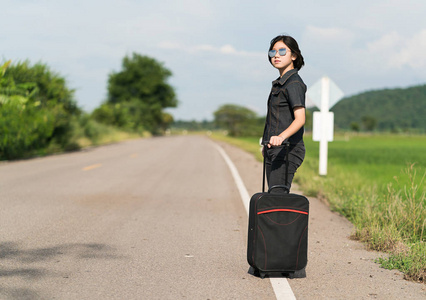 女人提着行李搭车沿着一条路