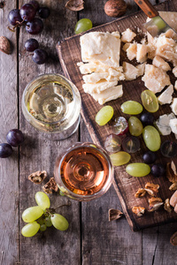 不同种类的奶酪 葡萄酒 水果和零食仿古木制的桌子上。静物的概念