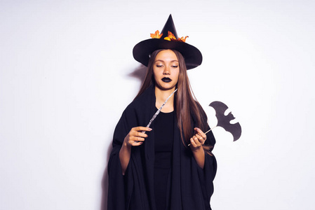 魔棒一个可怕的女孩 — — 巫婆在黑色的外套,帽子与秋天叶纸棒上举行