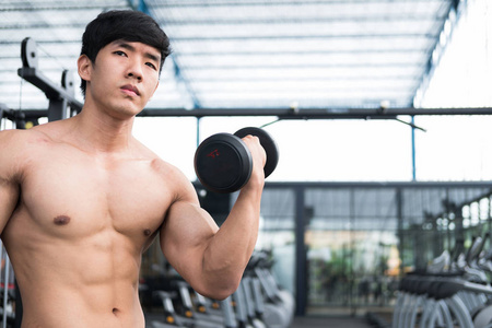 男子举哑铃在健身房。工作在 fitnes 的健美男