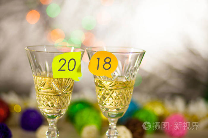 两杯香槟, 配上贴纸和2018年铭文。新年明亮模糊的背景