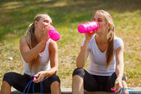 快乐的年轻女孩喝水后自然背景上的锻炼。健康的生活方式的概念