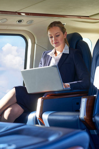 在航班不正常期间直升机座舱笔记本电脑上工作的女商人