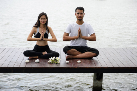 幸福的夫妇做瑜伽在码头上