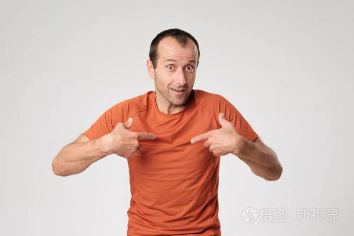 一个成人的西班牙人在橙色的 t 恤用他的手指指向自己