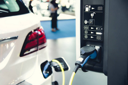 电动汽车的充电在停车场与电动汽车充电站在城市的街道上。在行准备充电的电动汽车