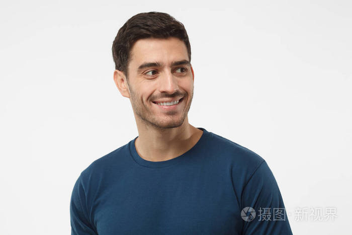 闭上微笑英俊的男性在蓝色tshirt的肖像向右看孤立的灰色背景